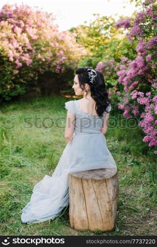 portrait of a brunette girl in a lilac spring garden before the wedding ceremony
