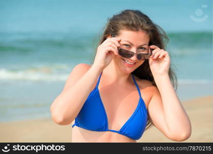 Portrait of a brunette in a blue bathing suit and sunglasses