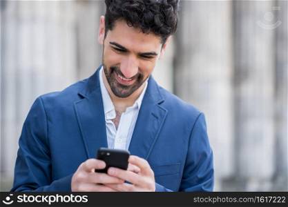Portrait of a business man using his mobile phone while standing outdoors on the street. Business and urban concept.