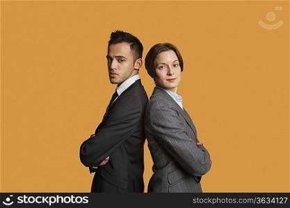 Portrait of a business partners standing back to back with arms crossed