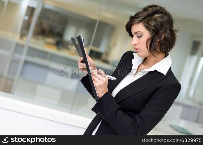 Portrait of a business woman in an office. Businesswoman writting with a folder in her hands in a modern office.