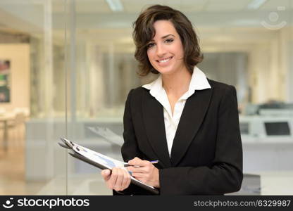 Portrait of a business woman in an office. Businesswoman writting with a folder in her hands in a modern office.