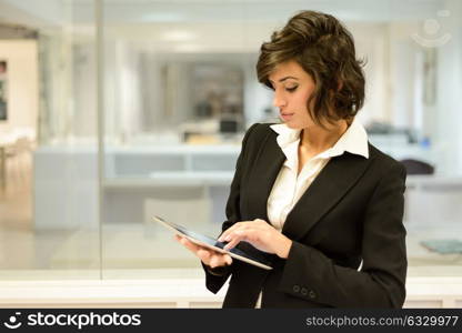 Portrait of a business woman looking at her tablet computer. Businesswoman in a modern office.