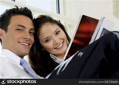 Portrait of a businessman and a businesswoman holding a magazine
