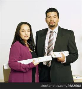 Portrait of a businessman and a businesswoman holding blueprints