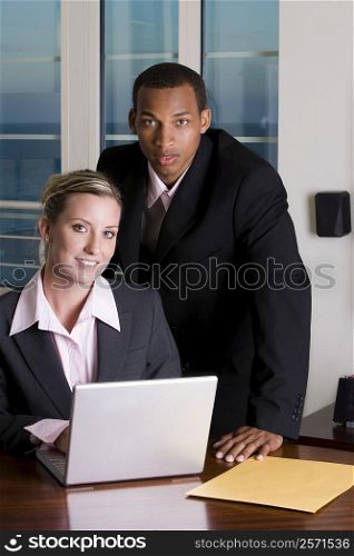 Portrait of a businessman and a businesswoman in front of a laptop