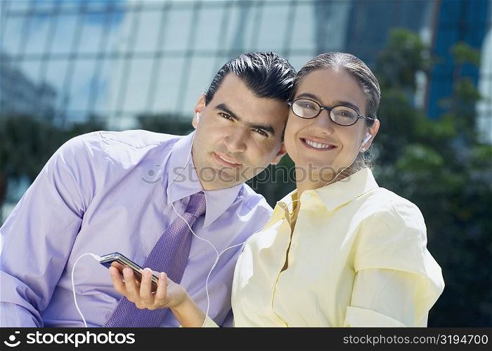 Portrait of a businessman and a businesswoman listening to an MP3 player