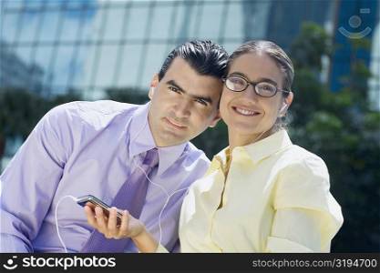 Portrait of a businessman and a businesswoman listening to an MP3 player