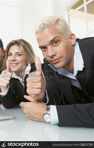 Portrait of a businessman and a businesswoman showing thumbs up signs