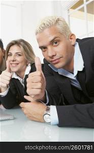Portrait of a businessman and a businesswoman showing thumbs up signs