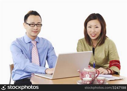 Portrait of a businessman and a businesswoman sitting in front of a laptop