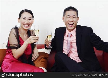 Portrait of a businessman and a mid adult woman holding glasses of champagne and laughing