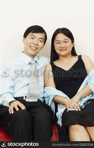 Portrait of a businessman and a mid adult woman sitting together on a couch and smiling