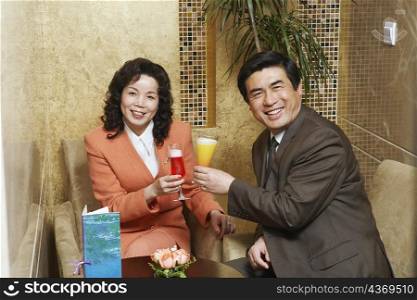 Portrait of a businessman and businesswoman sitting in a restaurant raising a toast