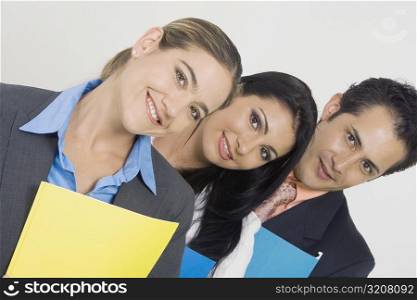 Portrait of a businessman and two businesswomen smiling and holding files