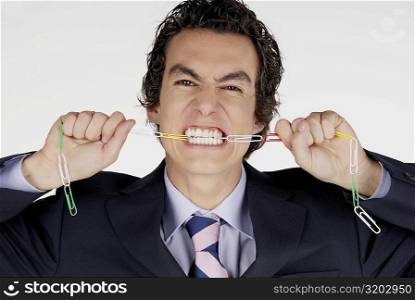 Portrait of a businessman biting a chain of paper clips