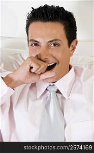 Portrait of a businessman covering his mouth with his hand while yawning