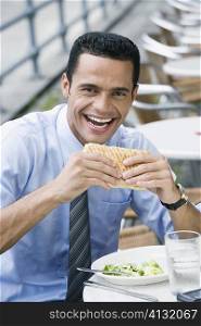 Portrait of a businessman eating a cheese sandwich and smiling