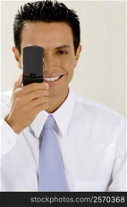 Portrait of a businessman hiding his eye with a mobile phone