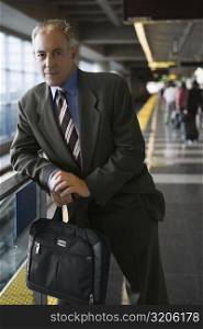 Portrait of a businessman holding a bag and standing at a subway station