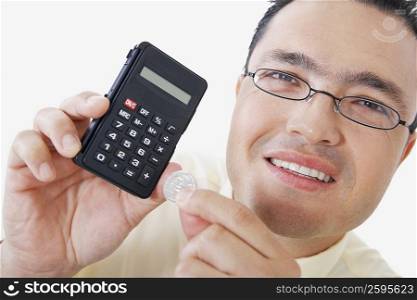 Portrait of a businessman holding a calculator and a coin