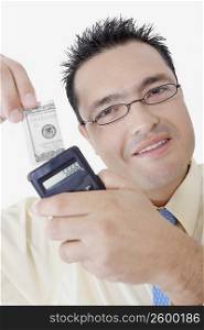 Portrait of a businessman holding a calculator and a dollar bill