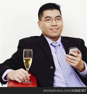 Portrait of a businessman holding a champagne flute and a mobile phone