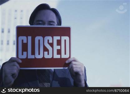 Portrait of a businessman holding a closed sign