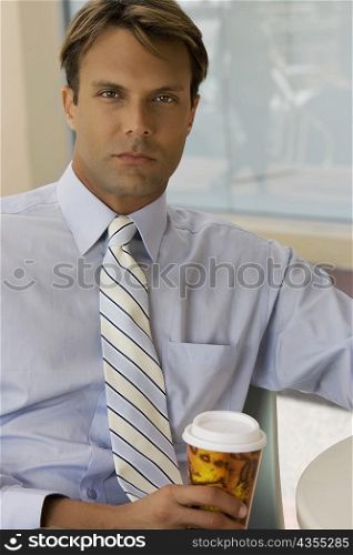 Portrait of a businessman holding a coffee cup in a cafe