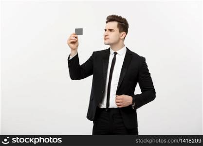 Portrait of a businessman holding a credit card and seriously checking isolated over grey background. Portrait of a businessman holding a credit card and seriously checking isolated over grey background.
