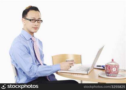 Portrait of a businessman holding a cup in front of a laptop