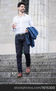 Portrait of a businessman holding a cup of coffee on way to work outdoors. Business concept.