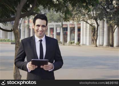 Portrait of a businessman holding a digital tablet , INDIA , DELHI