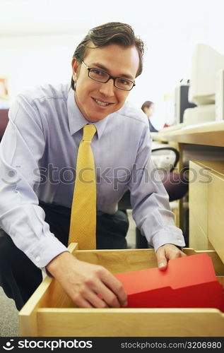 Portrait of a businessman holding a file in a drawer