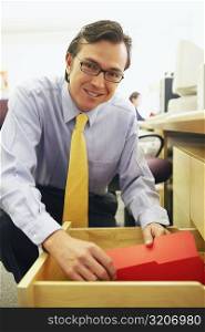 Portrait of a businessman holding a file in a drawer