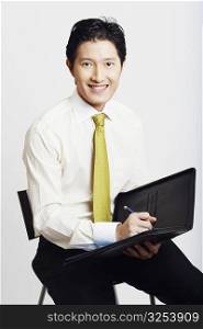 Portrait of a businessman holding a file with a pen and smiling