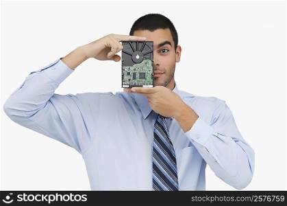 Portrait of a businessman holding a hard drive in front of his face