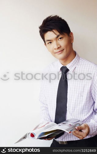 Portrait of a businessman holding a magazine and smirking