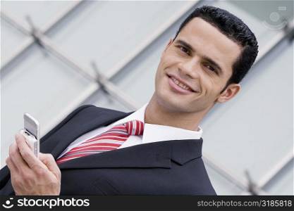 Portrait of a businessman holding a mobile phone and smiling