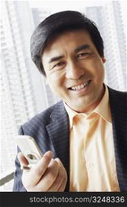 Portrait of a businessman holding a mobile phone smiling