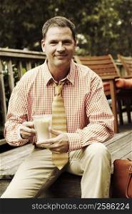 Portrait of a businessman holding a mug of milkshake and smiling