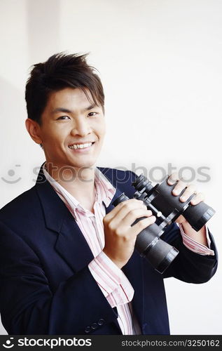 Portrait of a businessman holding a pair of binoculars and smiling