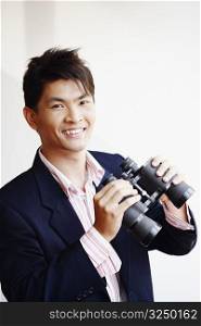 Portrait of a businessman holding a pair of binoculars and smiling