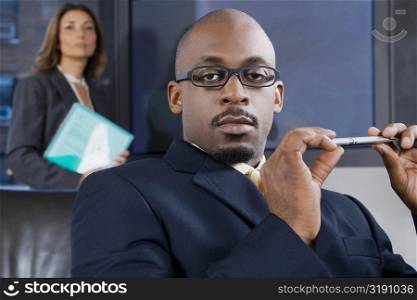 Portrait of a businessman holding a pen with his colleague standing behind him