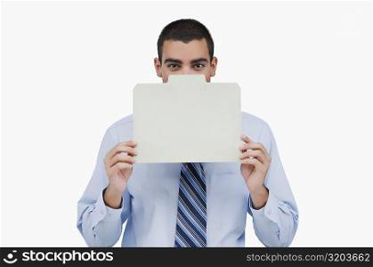 Portrait of a businessman holding a placard in front of his face