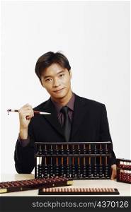 Portrait of a businessman holding a stick and using an abacus