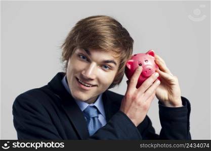 Portrait of a businessman holding and shaking piggy bank