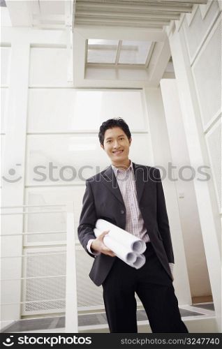Portrait of a businessman holding blueprints and smiling