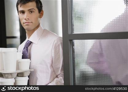 Portrait of a businessman holding disposable cups