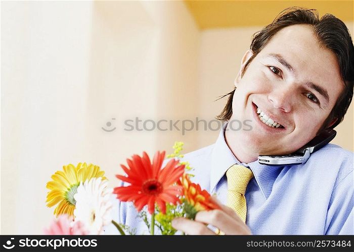 Portrait of a businessman holding flowers and talking on a mobile phone